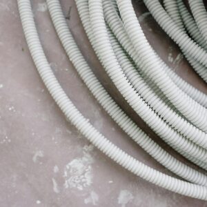 Close-up of coiled white electrical wire on a rough, textured concrete surface.